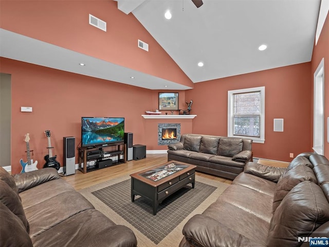 living room featuring beam ceiling, high vaulted ceiling, and light hardwood / wood-style flooring