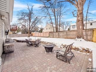 snow covered patio with an outdoor fire pit