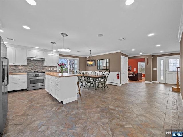 kitchen with decorative light fixtures, appliances with stainless steel finishes, a kitchen island, white cabinets, and backsplash