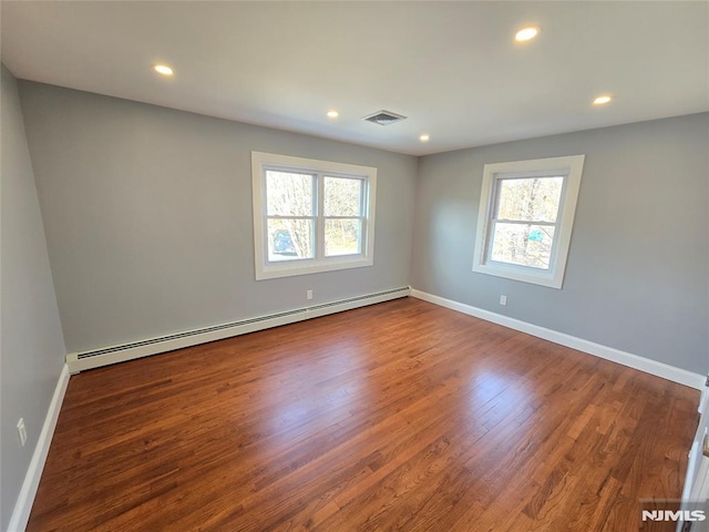 empty room with hardwood / wood-style flooring and a baseboard heating unit