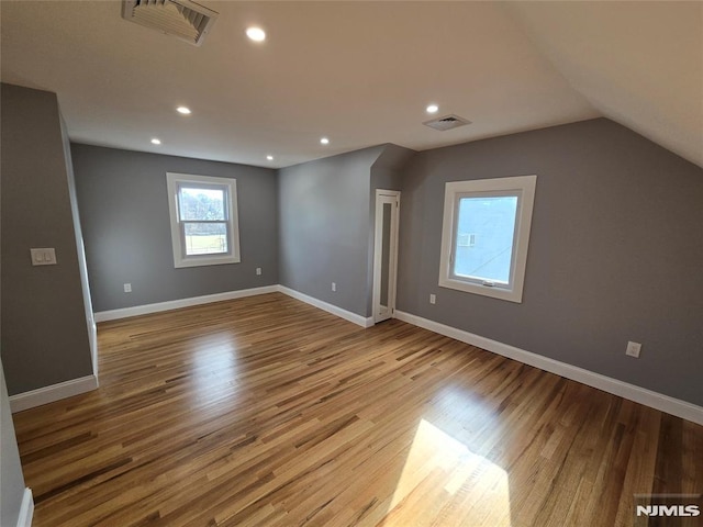 additional living space featuring vaulted ceiling and light hardwood / wood-style floors