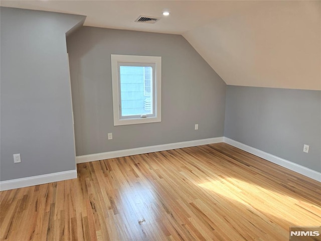 additional living space featuring lofted ceiling and light wood-type flooring