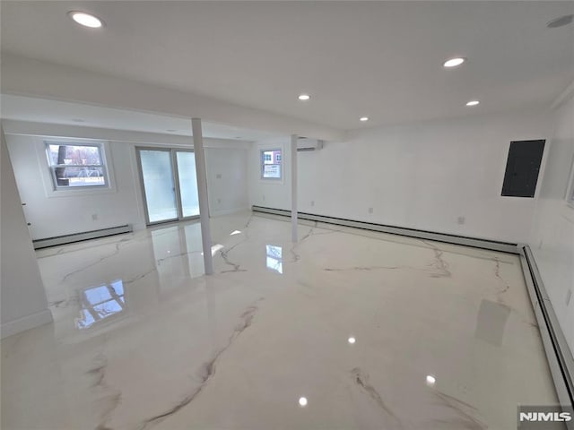 basement with a wealth of natural light, a wall mounted air conditioner, electric panel, and baseboard heating