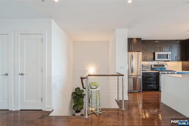 kitchen with appliances with stainless steel finishes, dark hardwood / wood-style flooring, and dark brown cabinets