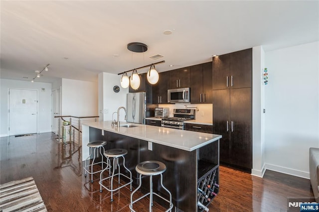 kitchen featuring a center island with sink, appliances with stainless steel finishes, dark hardwood / wood-style floors, and decorative light fixtures