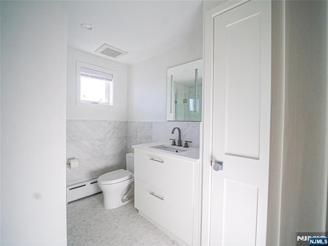 bathroom featuring vanity, toilet, tile walls, and a baseboard heating unit