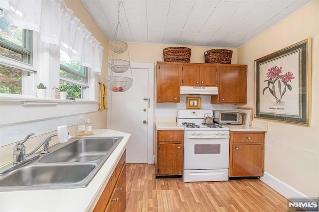 kitchen with white gas range, light hardwood / wood-style floors, and sink