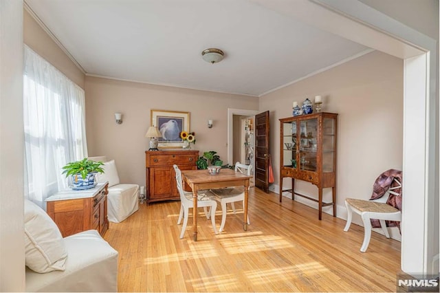 dining space with crown molding and light wood-type flooring