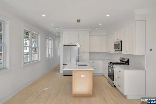 kitchen featuring stainless steel appliances, an island with sink, white cabinetry, and decorative backsplash