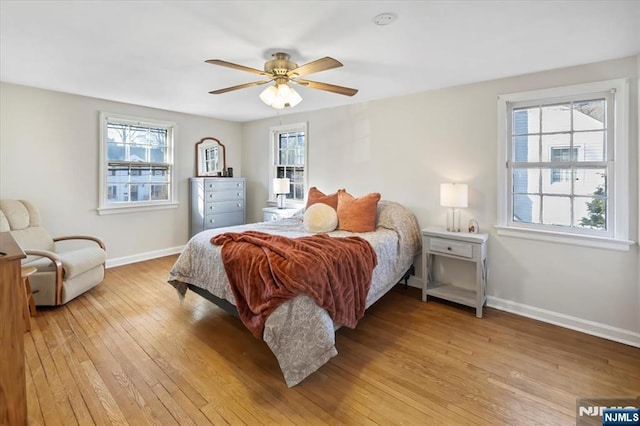 bedroom with ceiling fan, light hardwood / wood-style floors, and multiple windows