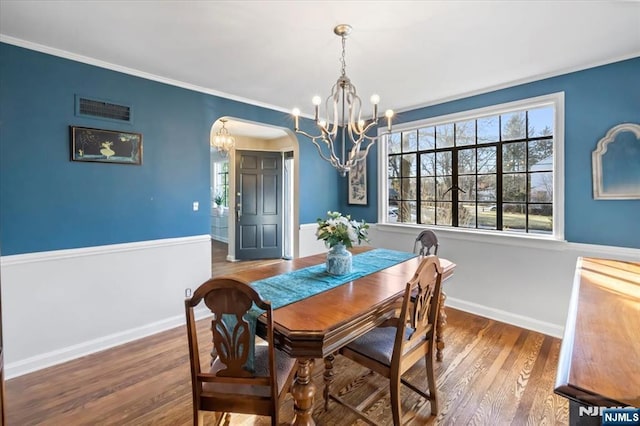 dining space featuring hardwood / wood-style flooring, ornamental molding, and a notable chandelier