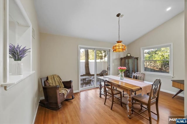 dining room with vaulted ceiling and light hardwood / wood-style flooring