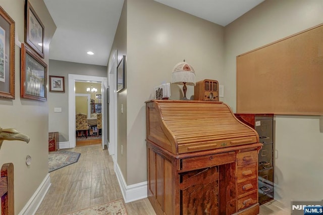 hallway featuring recessed lighting, a notable chandelier, baseboards, and light wood-style floors