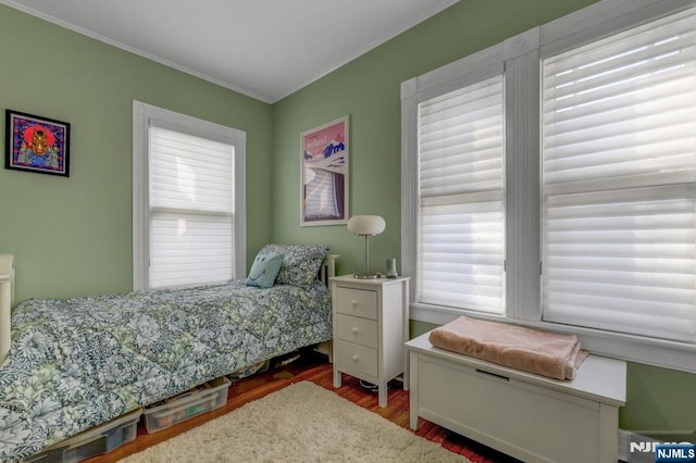 bedroom featuring multiple windows, wood finished floors, and crown molding