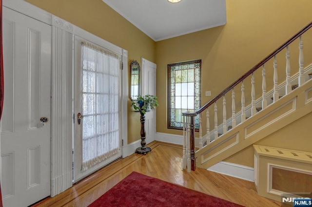 entryway featuring stairs, crown molding, wood finished floors, and baseboards