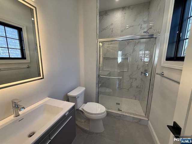 bathroom featuring vanity, a shower with shower door, and toilet