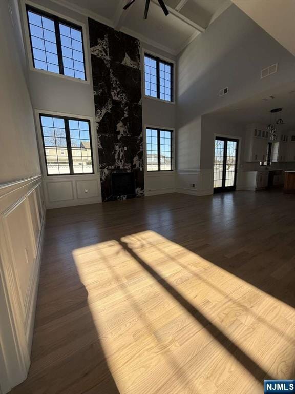 unfurnished living room featuring hardwood / wood-style flooring, coffered ceiling, beam ceiling, and french doors