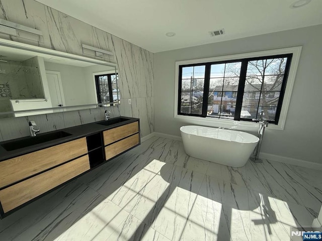 bathroom featuring plenty of natural light, a bathtub, and vanity