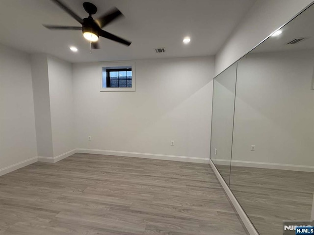 basement featuring ceiling fan and light hardwood / wood-style flooring