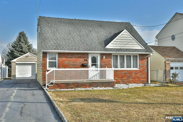 view of front of home with driveway, a detached garage, roof with shingles, an outbuilding, and brick siding