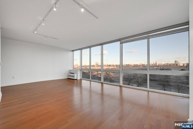 unfurnished room featuring floor to ceiling windows and wood-type flooring