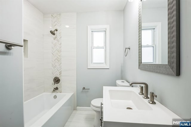 full bathroom featuring tiled shower / bath combo, vanity, and toilet