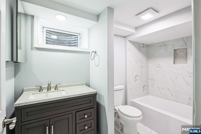 full bathroom featuring tiled shower / bath combo, vanity, and toilet