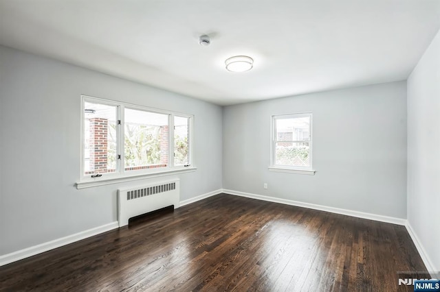 empty room featuring radiator heating unit and dark hardwood / wood-style flooring