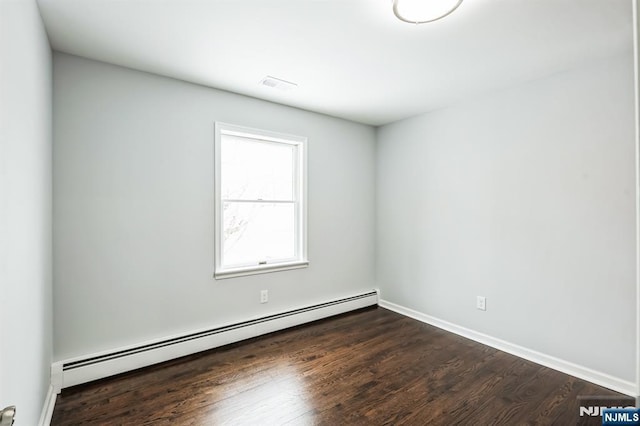 spare room featuring dark wood-type flooring and baseboard heating