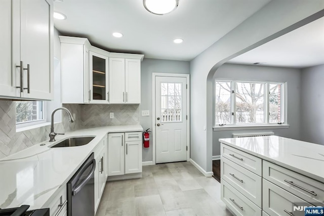 kitchen with light stone counters, dishwasher, sink, and white cabinets