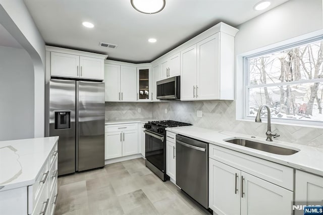 kitchen with light stone countertops, white cabinetry, appliances with stainless steel finishes, and sink