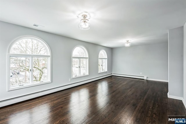 unfurnished room with a baseboard heating unit and dark hardwood / wood-style flooring