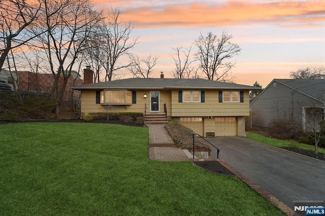 view of front of property featuring aphalt driveway, a lawn, a chimney, and an attached garage