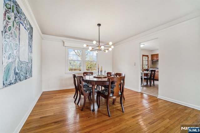 dining area with an inviting chandelier, baseboards, crown molding, and light wood-style floors