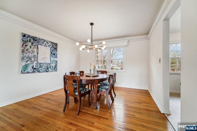 dining room with light wood finished floors, baseboards, an inviting chandelier, and ornamental molding