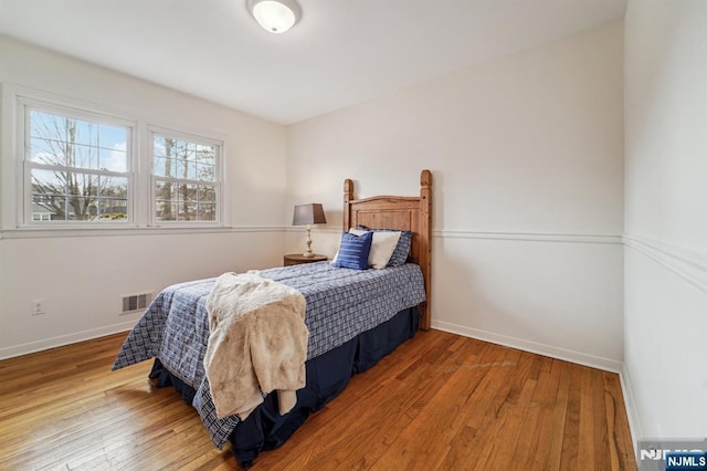 bedroom featuring visible vents, baseboards, and hardwood / wood-style flooring