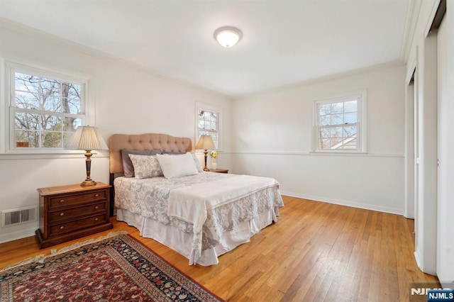 bedroom with light wood finished floors, visible vents, and multiple windows