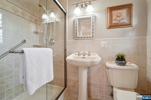 bathroom featuring tile walls, toilet, a stall shower, and wainscoting