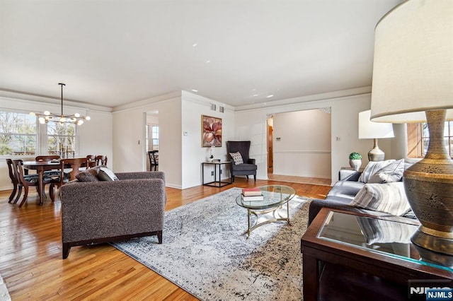 living area featuring a chandelier, light wood-style flooring, and crown molding