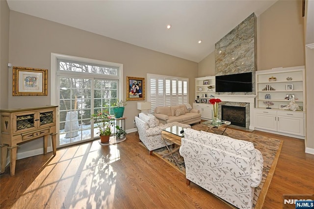 living room with hardwood / wood-style flooring, a fireplace, and high vaulted ceiling