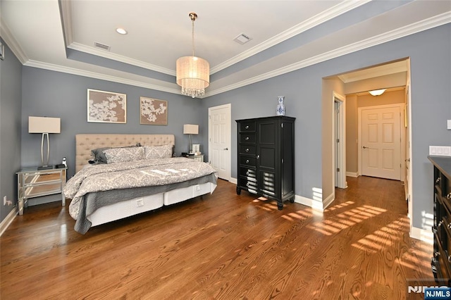 bedroom featuring dark hardwood / wood-style flooring, crown molding, a raised ceiling, and an inviting chandelier