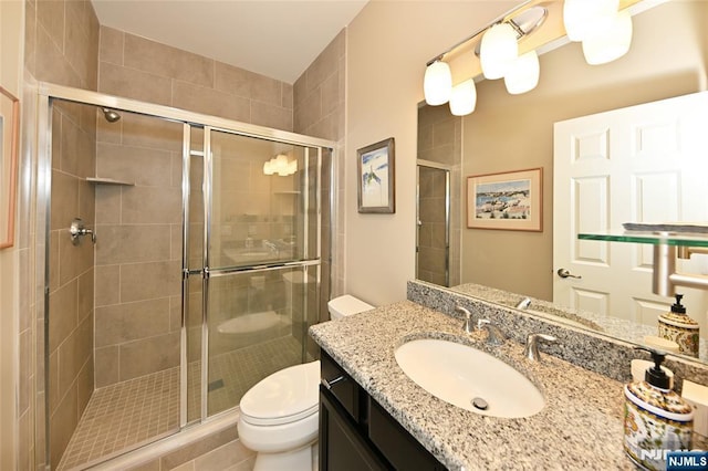 bathroom featuring toilet, vanity, and walk in shower