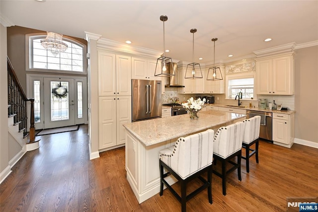 kitchen with light stone counters, a center island, hanging light fixtures, a kitchen breakfast bar, and stainless steel appliances