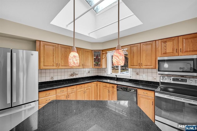 kitchen with appliances with stainless steel finishes, a skylight, hanging light fixtures, and dark stone counters