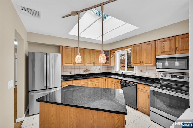 kitchen featuring a skylight, a center island, hanging light fixtures, dark stone countertops, and stainless steel appliances