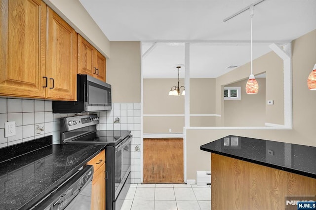 kitchen featuring decorative light fixtures, light tile patterned floors, dark stone counters, stainless steel appliances, and backsplash