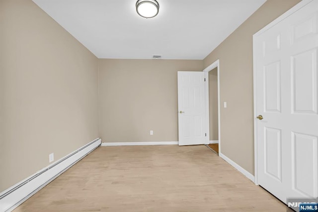 spare room with light hardwood / wood-style floors and a baseboard heating unit