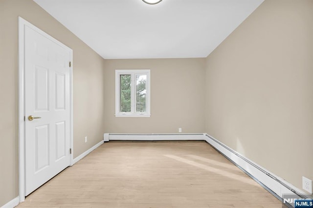 unfurnished room with a baseboard radiator and light hardwood / wood-style floors