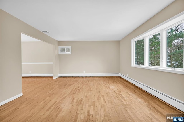 empty room featuring a baseboard heating unit and light hardwood / wood-style flooring