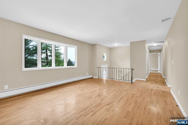 unfurnished room featuring a baseboard heating unit and light wood-type flooring